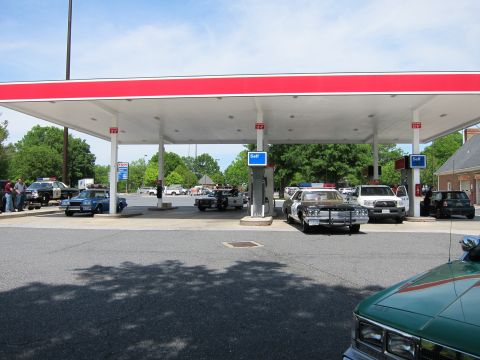 1991 Ford Crown Victoria - Several police cars are gathered at a gas station under a red and white awning.