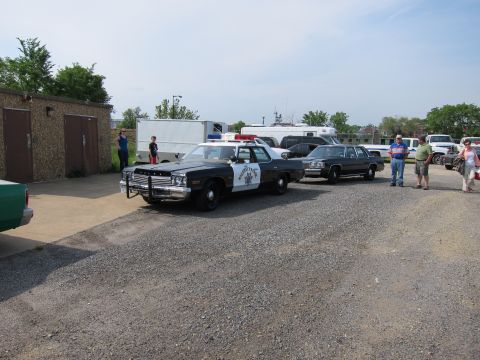 1991 Ford Crown Victoria - A vintage police car is displayed alongside other vehicles in an outdoor lot.