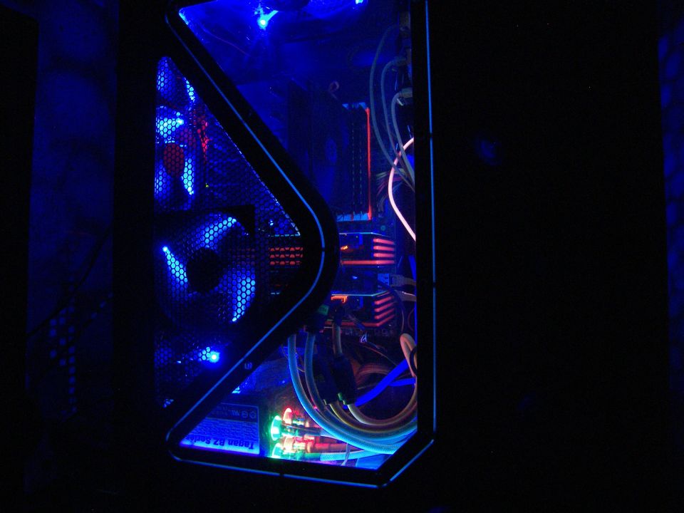 Computer case interior with blue LED fans and colorful cables visible through a clear side panel