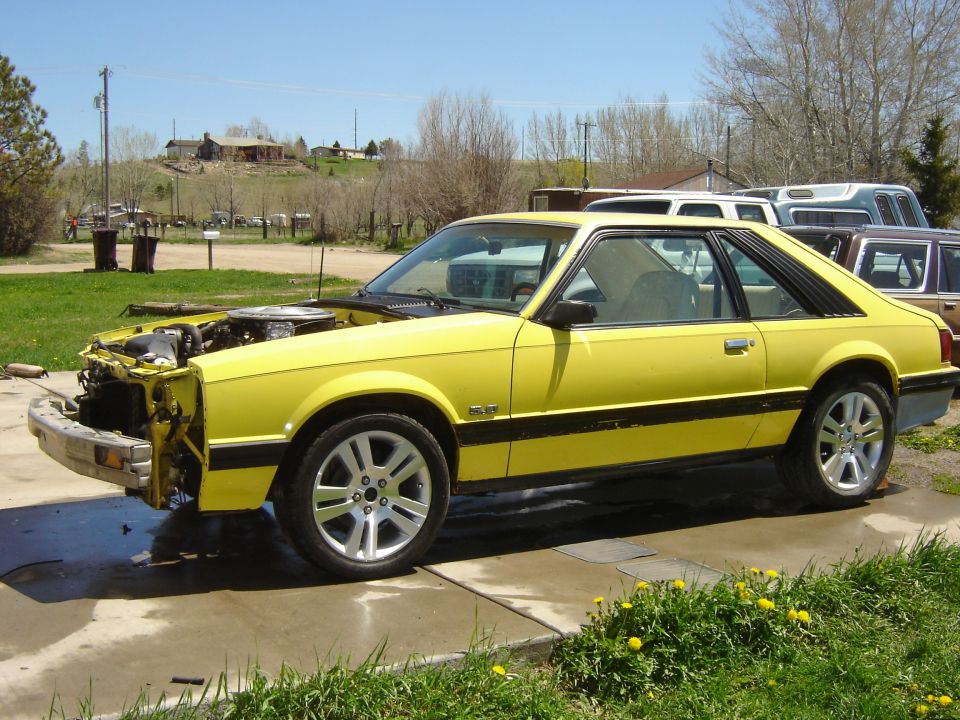 Yellow 1979 Ford Mustang coupe, hood open, front bumper removed