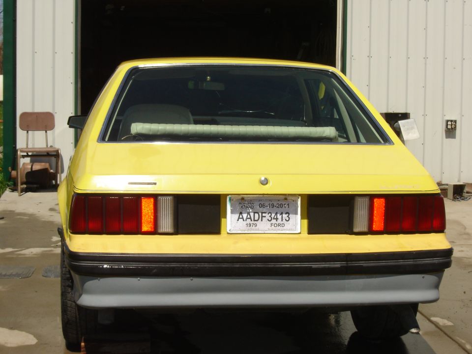 Rear view of a yellow 1979 Ford Mustang with a license plate reading AADF3413