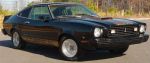 1977 Ford Mustang II - This black 1977 Ford Mustang II coupe is viewed from the front three-quarter angle, showing its distinctive body style and aftermarket whee…