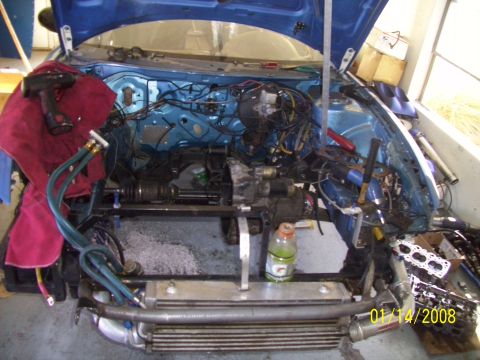 1995 Ford Probe - Two individuals are actively working on the engine compartment of a vehicle.