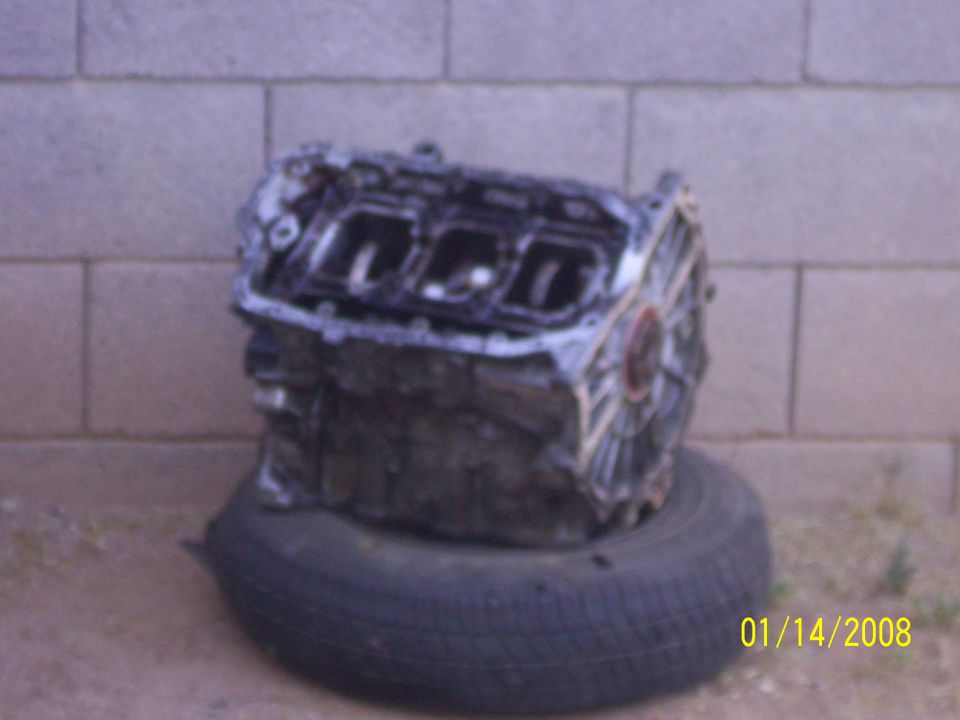 Engine block resting on a tire, against a brick wall
