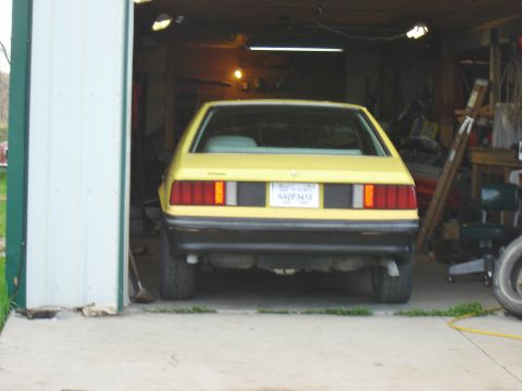 1979 Ford Mustang - Rear view of a yellow hatchback parked inside a garage.