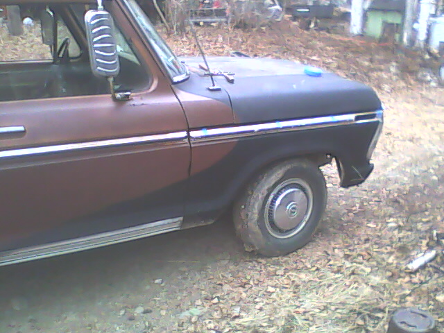 Side view of a brown and black Ford truck, showing the front fender and wheel
