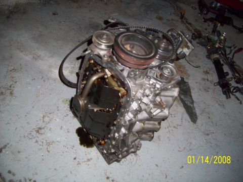 1995 Ford Probe - Engine block with oil pan removed, revealing internal parts and oil residue on the floor.