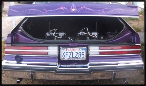 1991 Ford LTD Crown Victoria - The rear of a purple car is shown with its trunk open, revealing hydraulic components.