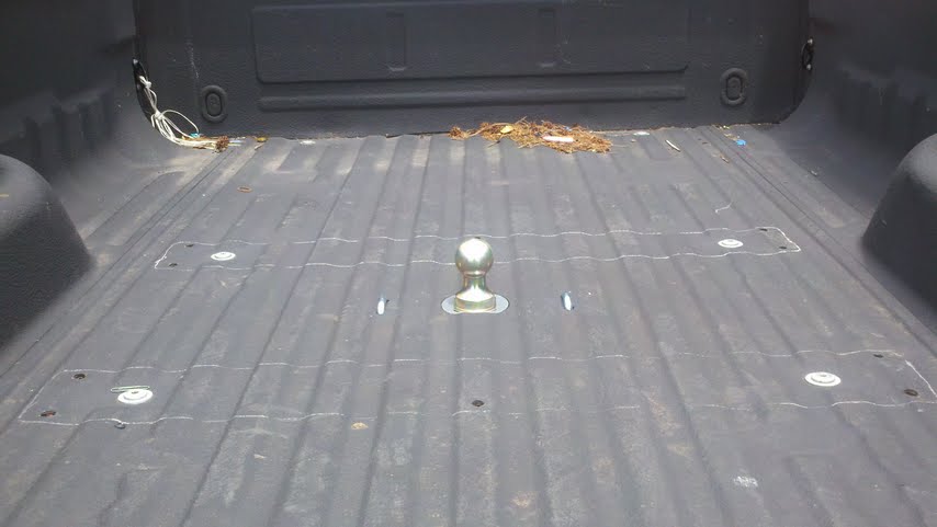 Truck bed interior showing a fifth wheel hitch assembly and tie-down points