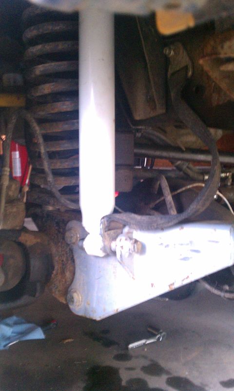 1978 Ford Bronco - Underside view of a vehicle's suspension system, focusing on the shock absorber and coil spring.