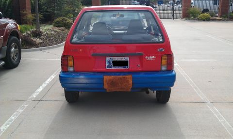 1991 Ford Festiva - Rear view of a red 1991 Ford Festiva with a blue bumper and a license plate.