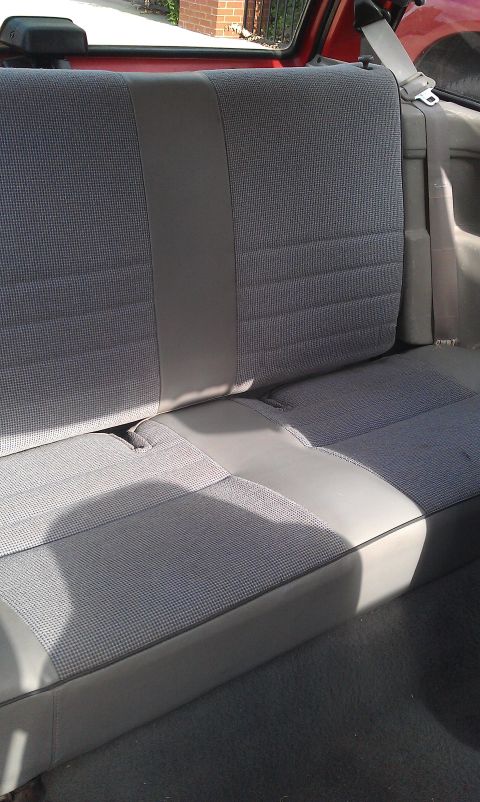 1991 Ford Festiva - Interior view of a gray patterned rear seat with a visible seatbelt.