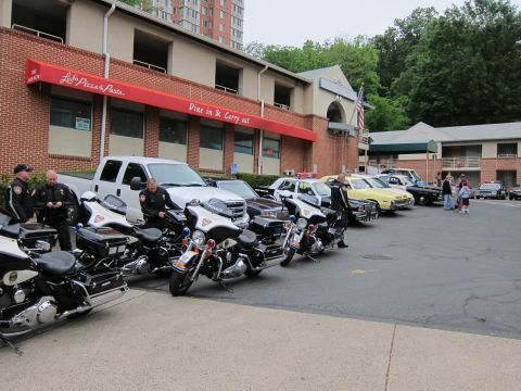 1991 Ford LTD Crown Victoria - row of police motorcycles with officers standing alongside, parked beside a brick building with a pizza restaurant sign.