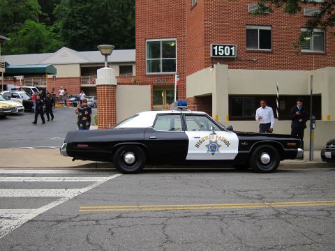 1991 Ford LTD Crown Victoria - black-and-white Highway Patrol sedan parked at a crosswalk on a street in front of a brick building numbered 1501.