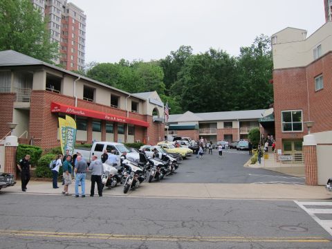 1991 Ford LTD Crown Victoria - Police motorcycles and classic cars lined up in a parking lot beside a brick conference center, with people gathered nearby.