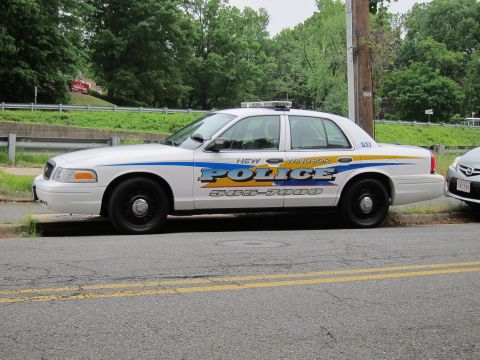 1991 Ford LTD Crown Victoria - white New Windsor Police Crown Victoria parked at the curb of a road with a guardrail and trees behind it.