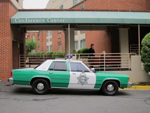 1991 Ford LTD Crown Victoria - green and white Ford LTD Crown Victoria Sheriff car with a single roof light parked under a Conference Center canopy.