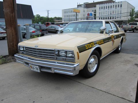 1991 Ford LTD Crown Victoria - Front three-quarter view of a tan Chevrolet State Police sedan with a single dome light, parked along a street with cars behind.