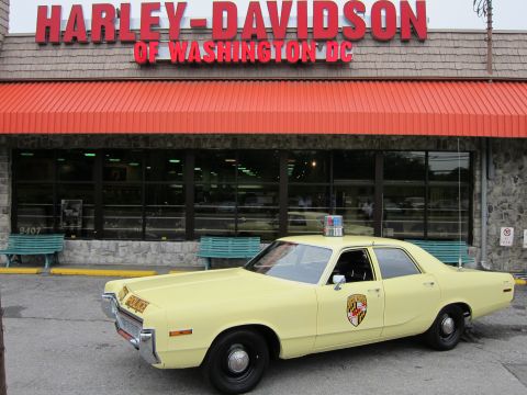 1991 Ford LTD Crown Victoria - yellow Police sedan parked in profile under the large red Harley-Davidson of Washington DC sign and orange awning.