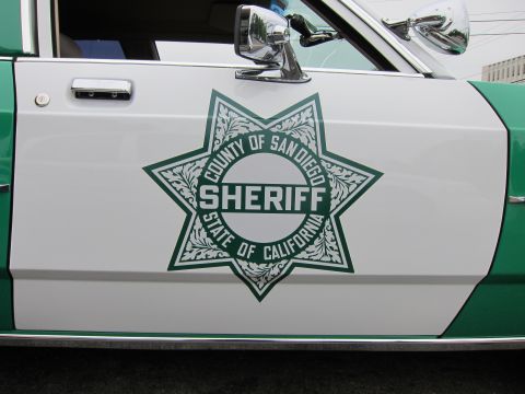 1991 Ford LTD Crown Victoria - Close-up of a green-and-white car door bearing the seven-point County of San Diego, State of California Sheriff star decal.