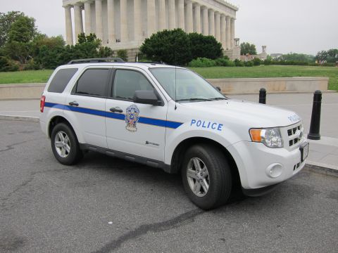 1991 Ford LTD Crown Victoria - white Ford Escape hybrid Police SUV with a blue stripe is parked in front of the columned Lincoln Memorial.