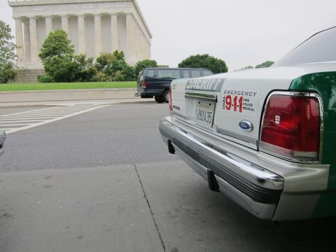 1991 Ford LTD Crown Victoria - Close rear-corner view of a green-and-white Sheriff Ford sedan marked Dial 911, with the Lincoln Memorial in the background.