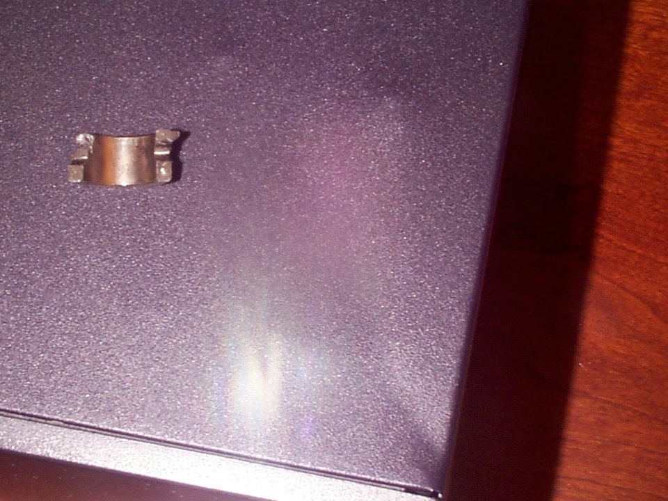Small metal clamp resting on a dark, textured surface