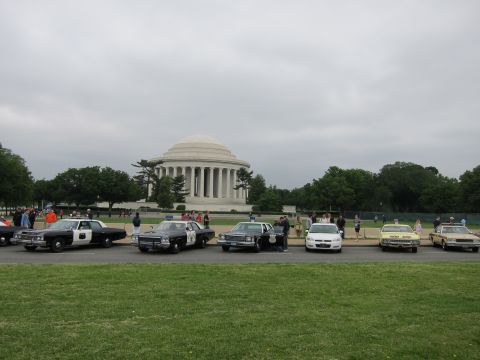 1991 Ford LTD Crown Victoria - lineup of vintage police cars sits on a lawn with the domed Jefferson Memorial behind them under a grey sky.