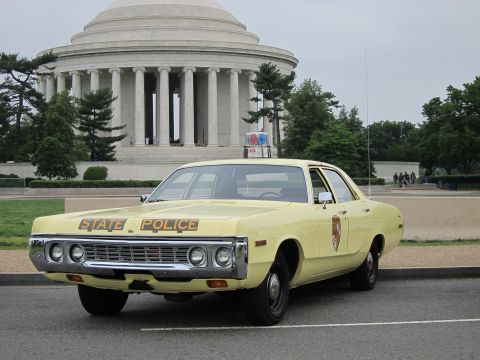 1991 Ford LTD Crown Victoria - yellow vintage State Police sedan is parked in front of the columned Jefferson Memorial under a grey sky.