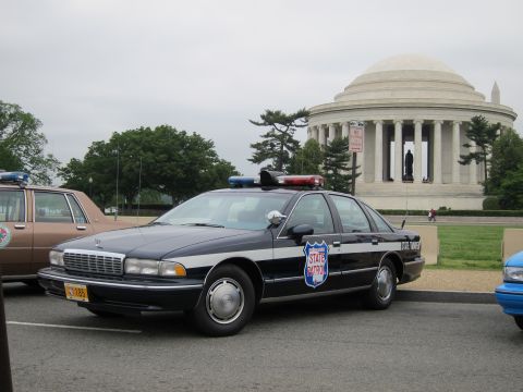 1991 Ford LTD Crown Victoria - dark blue State Trooper Chevrolet Caprice with a roof light bar sits before the columned Jefferson Memorial.