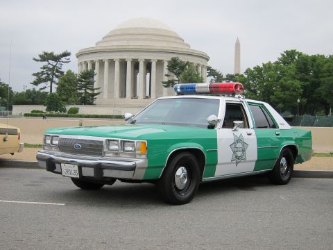 1991 Ford LTD Crown Victoria - Front three-quarter view of a green-and-white Ford sheriff cruiser with star decal, the Jefferson Memorial behind it.