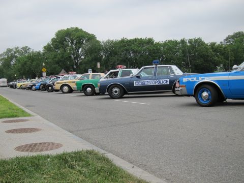 1991 Ford LTD Crown Victoria - long line of vintage police cruisers parked along a curb, with North Haven Police and blue cars in the foreground.
