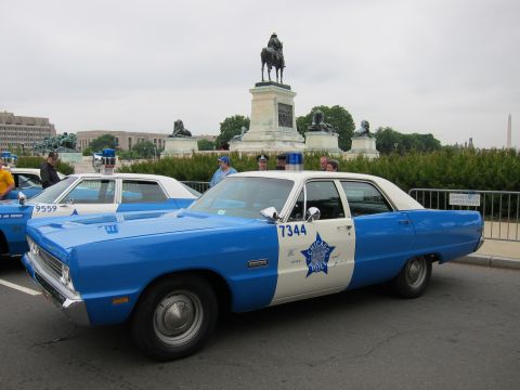 1991 Ford LTD Crown Victoria - blue and white classic police sedan marked 7344 with a star emblem is parked near a DC equestrian statue and the Washington Monument.