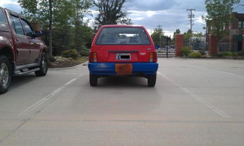 1991 Ford Festiva - Rear view of a 1991 Ford Festiva with a custom blue bumper and fuzzy license plate cover.