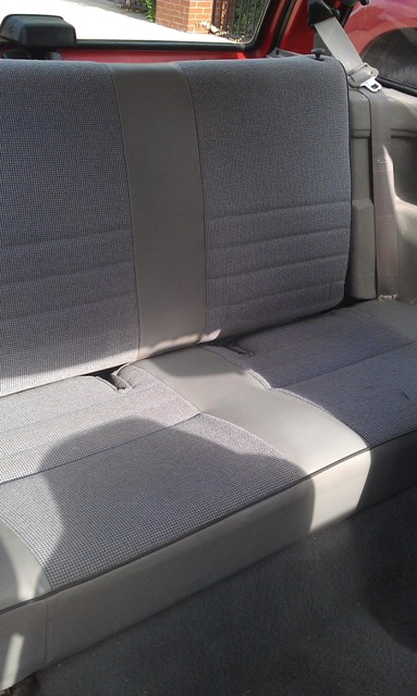 1991 Ford Festiva - Interior view of gray fabric rear car seats with a dark gray center panel and a gray seatbelt visible.
