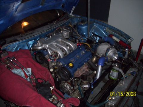 1995 Ford Probe - The engine bay is open, revealing a turbocharger setup and various tools laid out on a red cloth.
