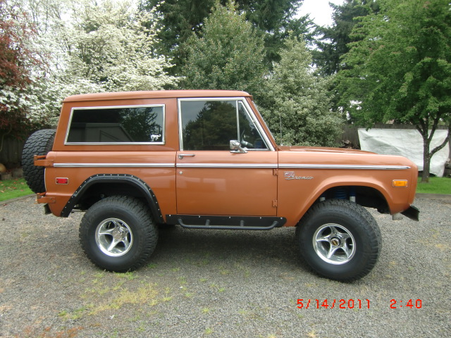 Orange 1973 Ford Bronco with spare tire on rear, side view