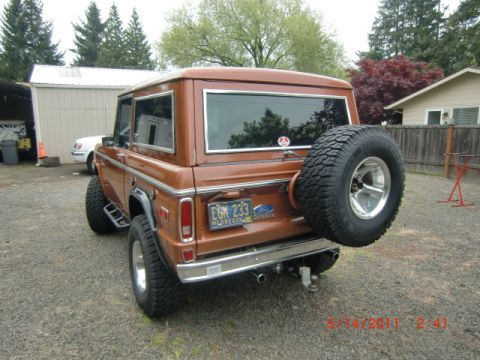 1973 Ford Bronco - Rear view of a brown 1973 Ford Bronco, a spare tire on the tailgate and a "Supermotors" watermark.
