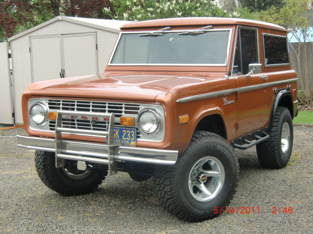 Orange Ford Bronco with chrome grille guard and aftermarket wheels