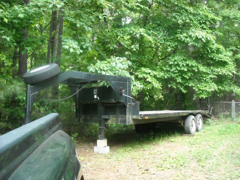 1979 Ford F-150 - Gooseneck trailer with spare tire, parked outdoors near trees and a fence.