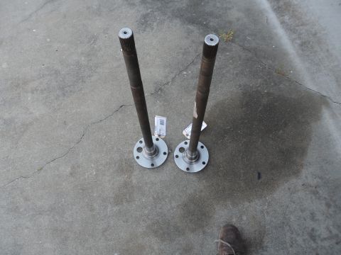 1991 Ford Bronco - Two axle shafts are laid out on a concrete surface, each with a flange at one end and splines at the other.