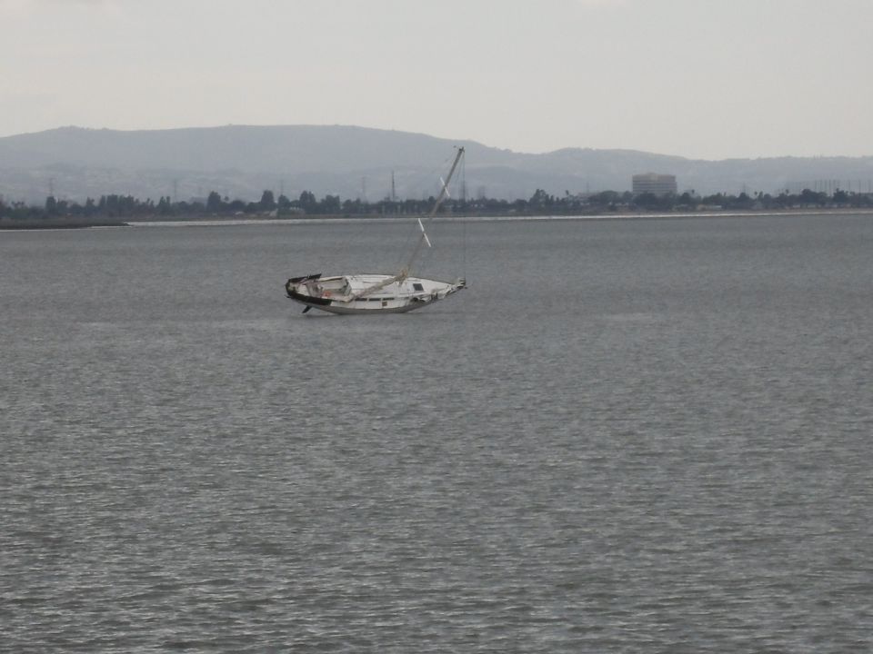 Sailboat listing in water, mast broken, hull damaged