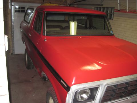 1979 Ford Bronco - This red SUV, likely from the late 1970s, is shown from a 3/4 front angle inside a garage.