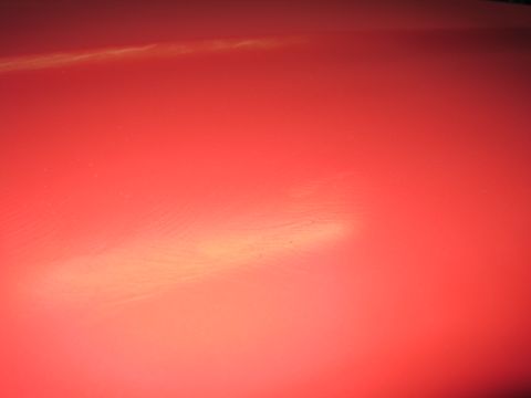 1979 Ford Bronco - A close-up shot of a red car's hood shows subtle reflections and texture.