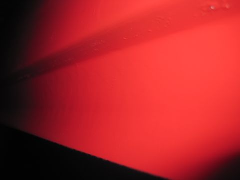 1979 Ford Bronco - A close-up of a red metal panel, possibly a vehicle body part, with a dark stripe and a Supermotors logo visible.
