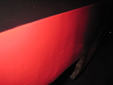 1979 Ford Bronco - Scratched red painted metal panel, possibly part of a vehicle body.