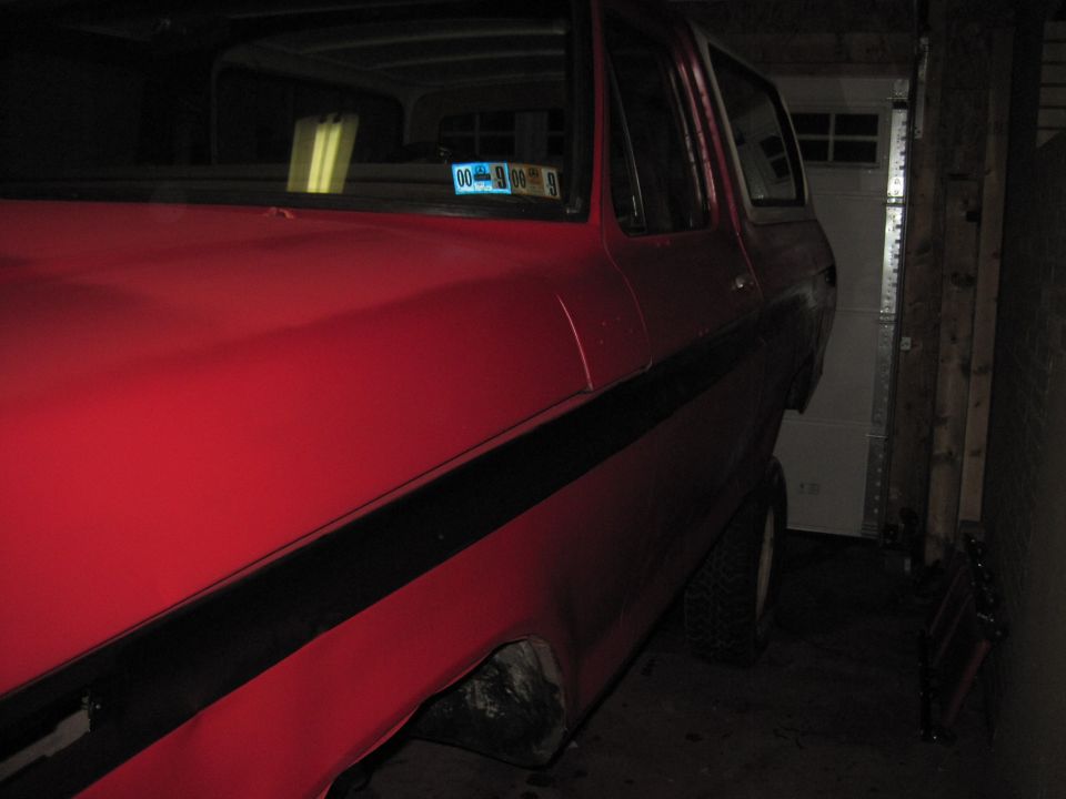 Red SUV with black side stripe, parked in a garage. Visible license plate