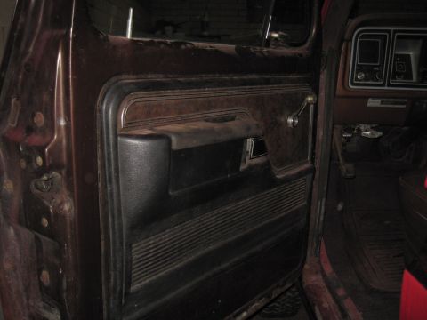 1979 Ford Bronco - Interior view of a car door panel and dashboard, showing a brown and black color scheme with ribbed textures.