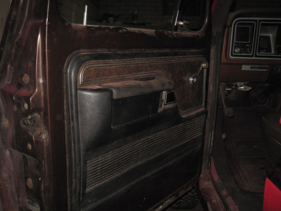 Brown and black car door panel with chrome handle and ribbed texture; dashboard visible
