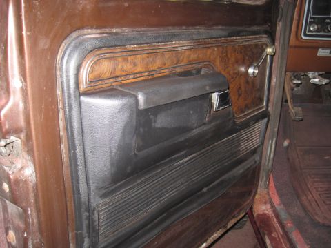 1979 Ford Bronco - The interior door panel of a 1979 Ford Bronco features wood grain trim and a black armrest.